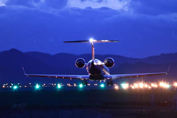 夜に近づく空港の景色を見ながら、搭乗前の時間を過ごしている写真