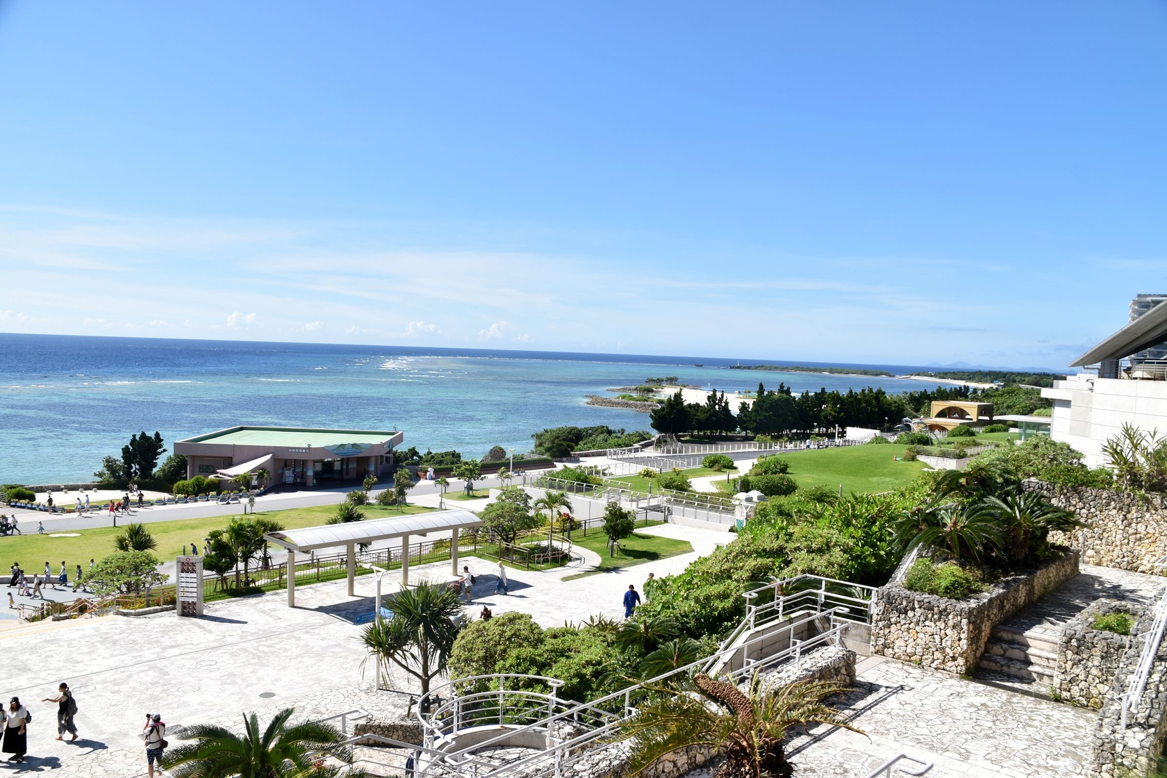 強い日差しの中で海と砂浜が輝いて見える沖縄の海の写真